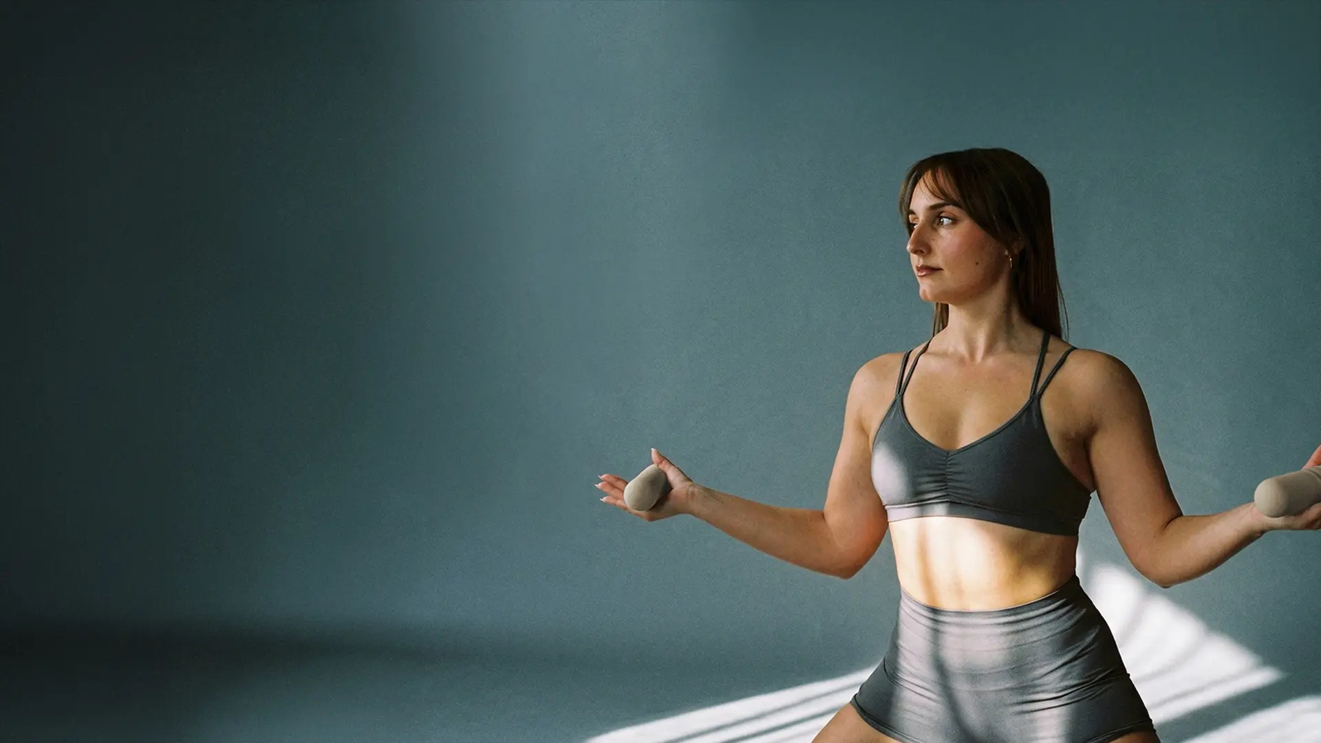 Mujer entrenando pilates de alto rendimiento con pesas